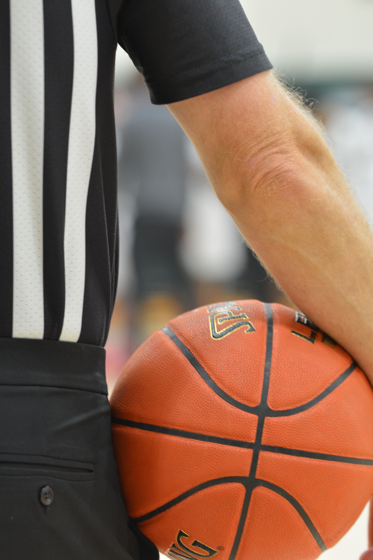 Basketball referee in uniform holding a game ball